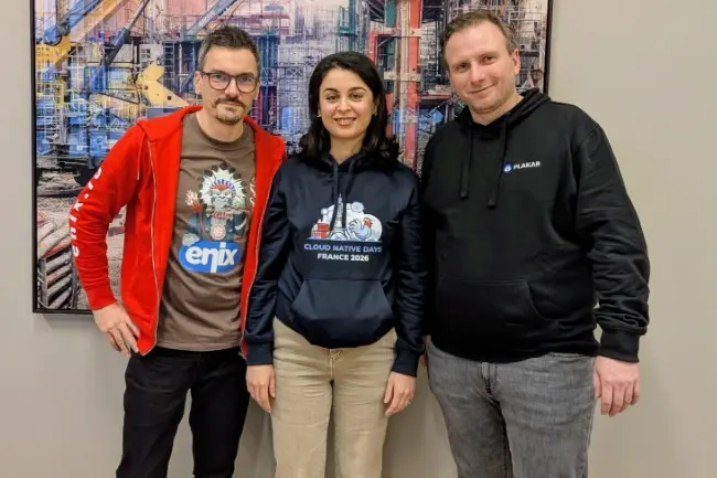 Trois personnes souriantes posent ensemble pour une photo. Elles portent des tenues décontractées arborant des logos liés au secteur de la tech