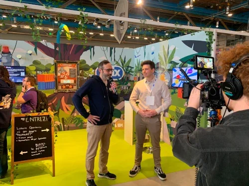 Photo de Nicolas en train de répondre à un journaliste sur nos activité cloud native devant notre stand KCD France 2023